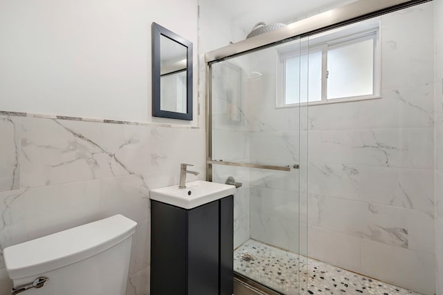 bathroom with a shower with door, vanity, toilet, and tile walls