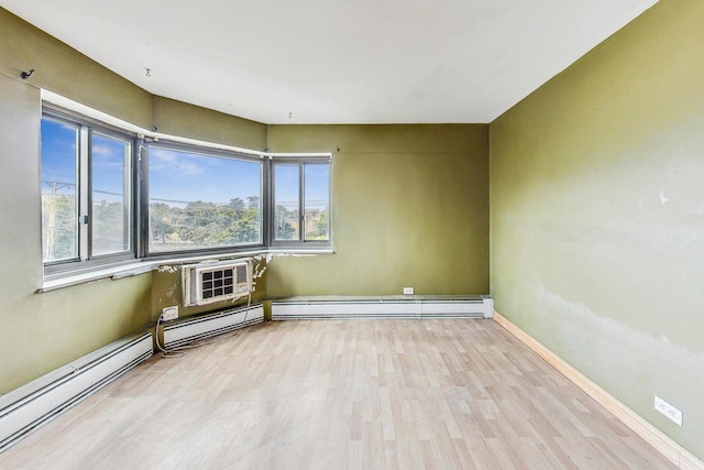 spare room with light hardwood / wood-style flooring, a baseboard radiator, and a wall mounted air conditioner