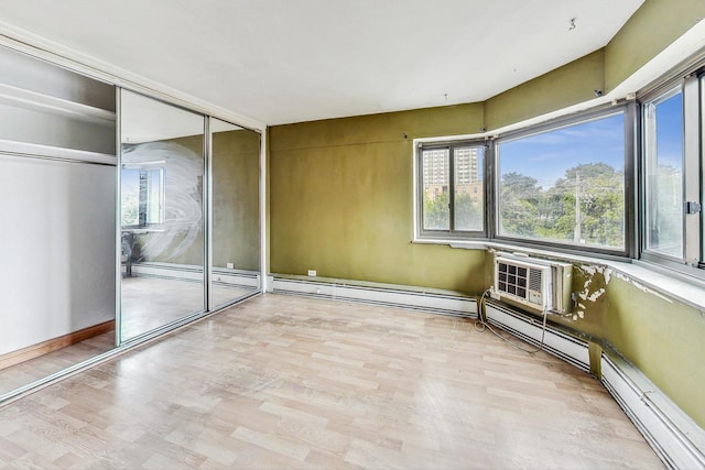 unfurnished room with a wealth of natural light, a wall unit AC, and light hardwood / wood-style floors