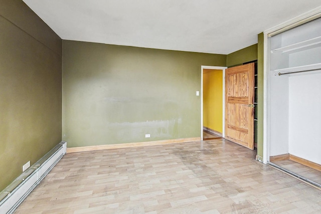 unfurnished bedroom featuring light hardwood / wood-style floors, a baseboard radiator, and a closet