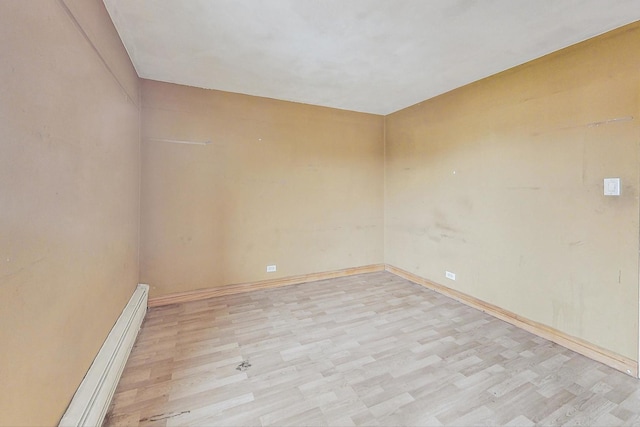 spare room featuring light wood-style flooring and a baseboard heating unit