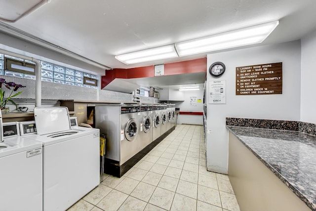 clothes washing area featuring washer and clothes dryer and light tile patterned floors