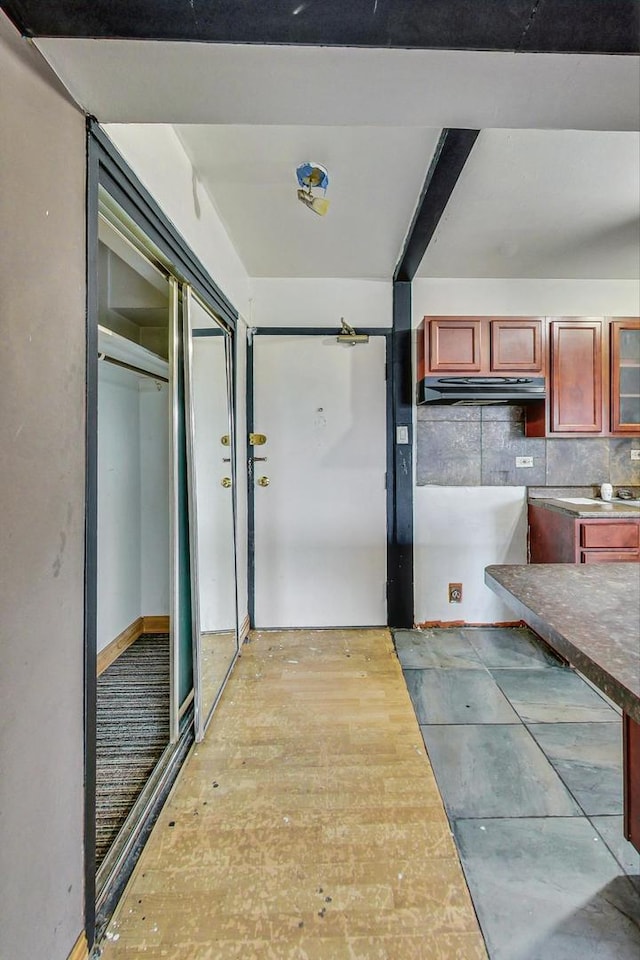 interior space with reddish brown cabinets and under cabinet range hood