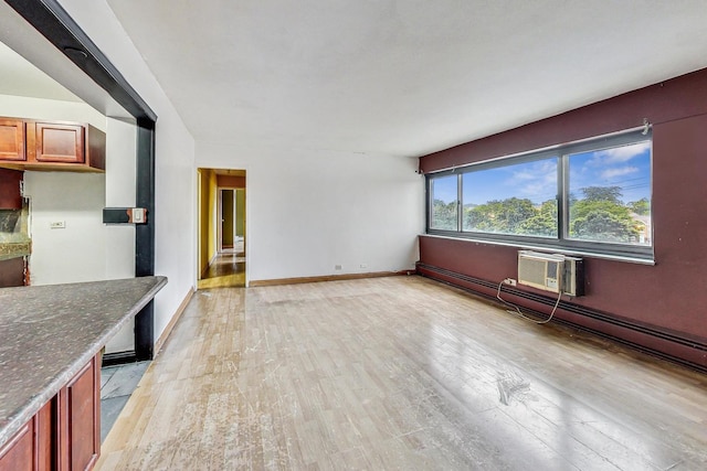 unfurnished living room featuring baseboards, a wall mounted air conditioner, and light wood-style flooring