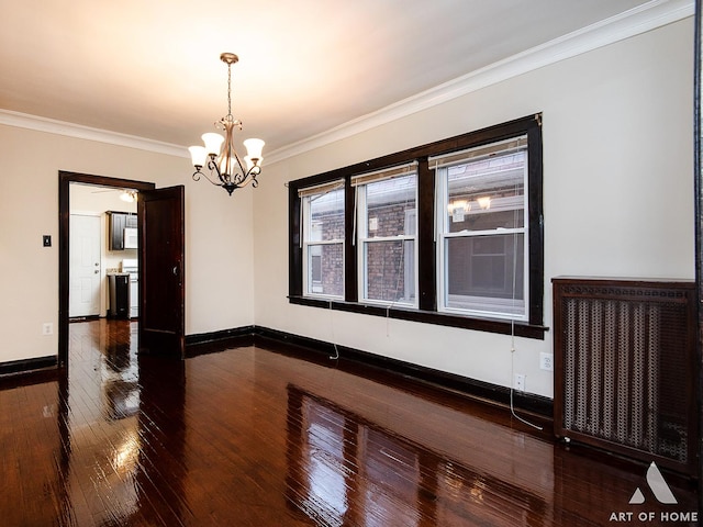 empty room with hardwood / wood-style floors, crown molding, and a notable chandelier