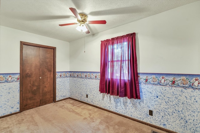 carpeted empty room with a textured ceiling and ceiling fan