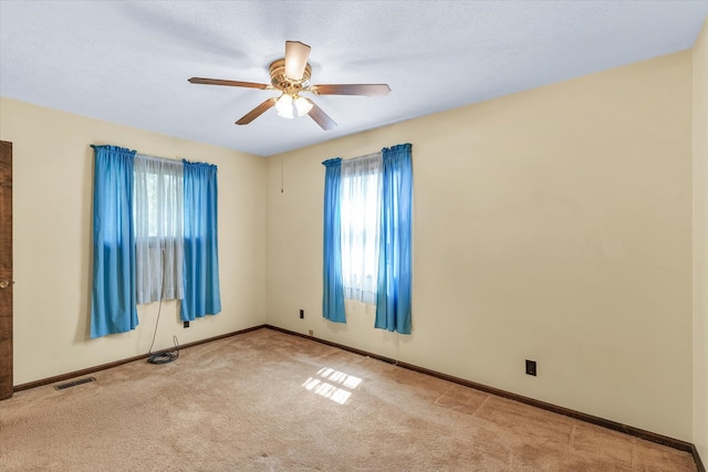 carpeted spare room with ceiling fan and a wealth of natural light