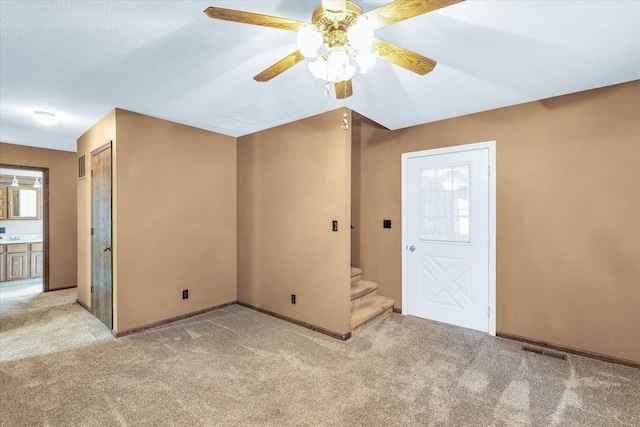 interior space with ceiling fan and light colored carpet