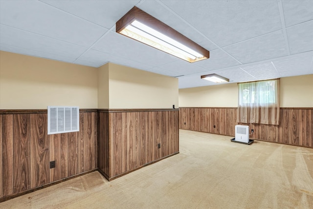 basement featuring a paneled ceiling and light carpet