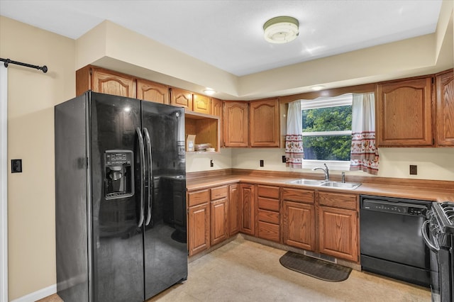 kitchen featuring sink, black appliances, a barn door, and light tile patterned floors