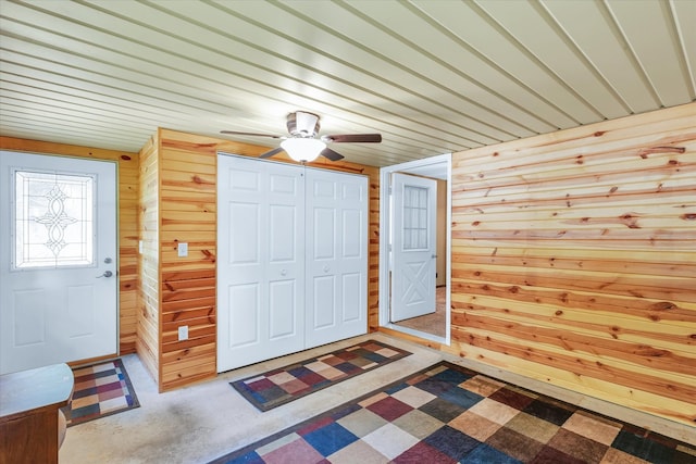 foyer featuring ceiling fan and wooden walls