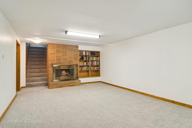 unfurnished living room with a brick fireplace, built in shelves, and carpet flooring