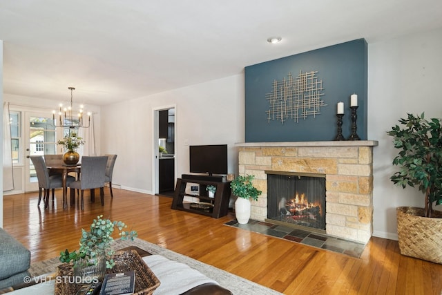 living room featuring wood-type flooring, an inviting chandelier, and a fireplace