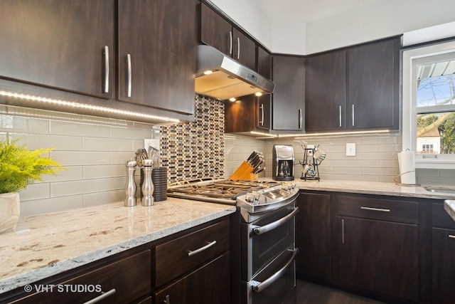 kitchen featuring light stone countertops, dark brown cabinets, backsplash, and range with two ovens