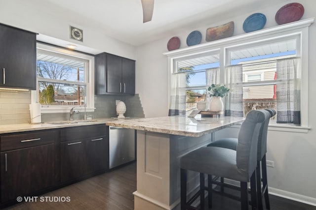 kitchen with dishwasher, a healthy amount of sunlight, decorative backsplash, sink, and a breakfast bar