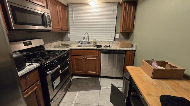 kitchen featuring stainless steel appliances, light tile patterned flooring, sink, and light stone counters