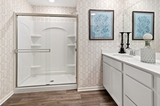 bathroom with a shower with shower door, hardwood / wood-style floors, and vanity