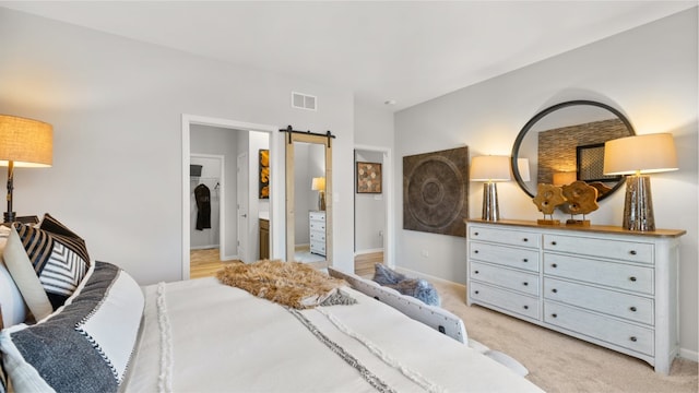 bedroom featuring light colored carpet and a barn door