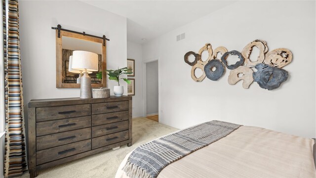 bedroom featuring light colored carpet and a barn door