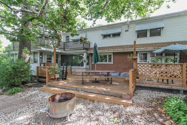 back of house featuring a wooden deck and an outdoor fire pit