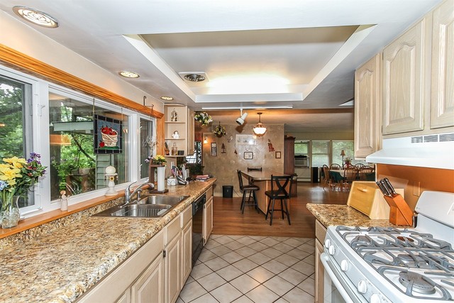 kitchen featuring light tile patterned flooring, a raised ceiling, plenty of natural light, and white range with gas cooktop