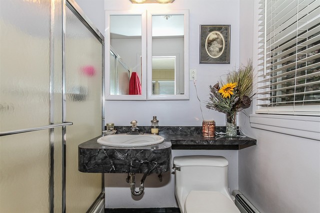 bathroom featuring a baseboard heating unit, sink, toilet, and an enclosed shower