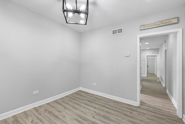 spare room with hardwood / wood-style floors and a chandelier