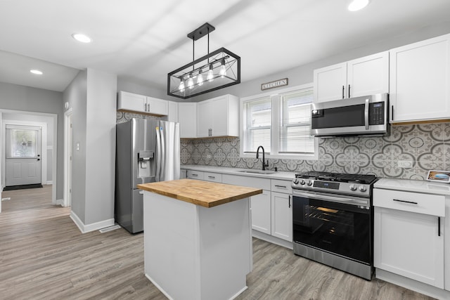 kitchen with appliances with stainless steel finishes, a kitchen island, backsplash, and light hardwood / wood-style flooring