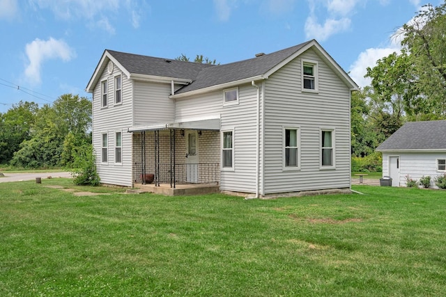 rear view of property with a shingled roof and a lawn