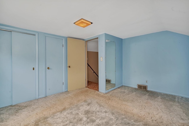 unfurnished bedroom with lofted ceiling, carpet flooring, and visible vents