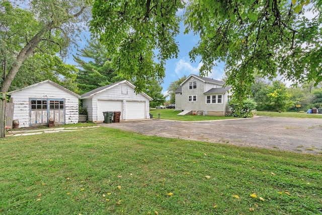 view of front of property with a detached garage, a front lawn, and an outdoor structure