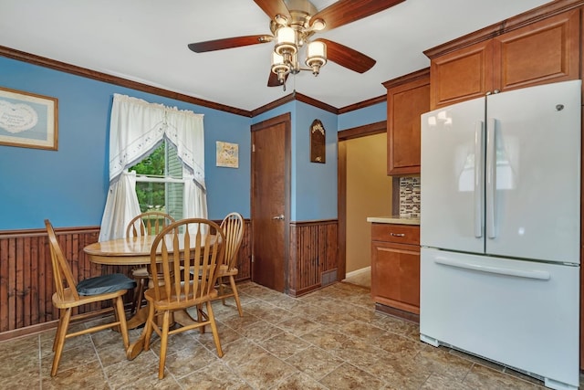 dining room featuring a wainscoted wall, crown molding, and wooden walls