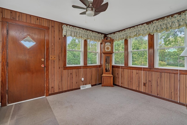 foyer entrance with light colored carpet, visible vents, wood walls, and baseboards