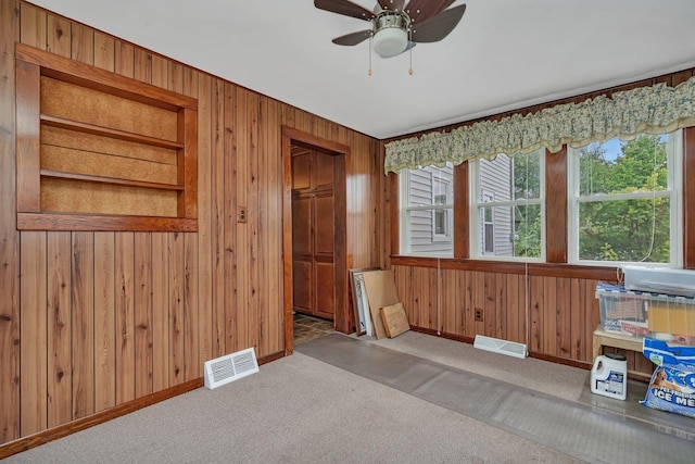 unfurnished room with carpet floors, visible vents, and wooden walls