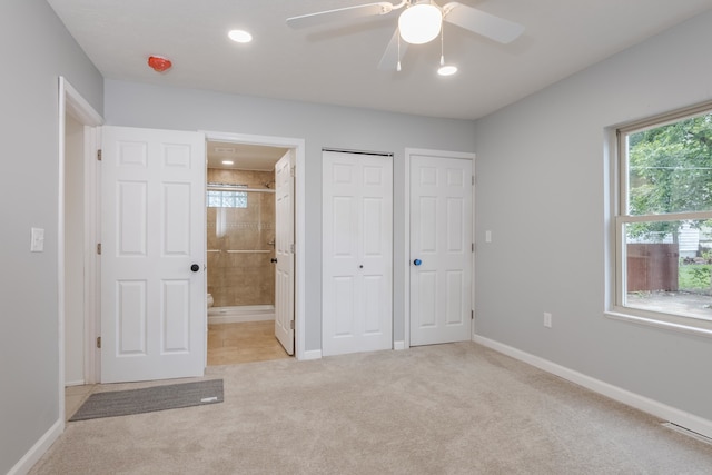 unfurnished bedroom with ceiling fan, light colored carpet, and ensuite bath