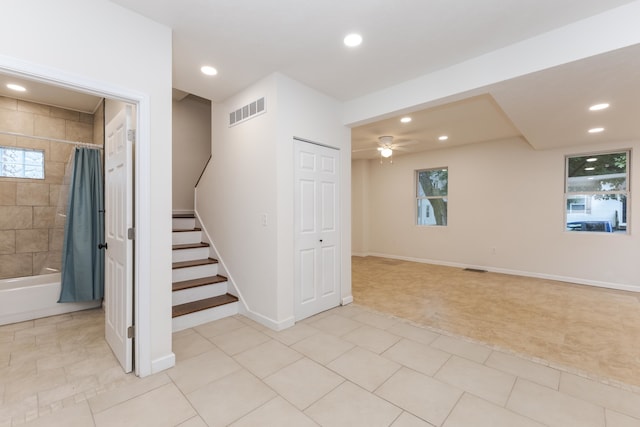 basement featuring ceiling fan, plenty of natural light, and light tile patterned flooring