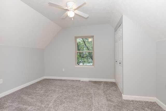 additional living space featuring light carpet, vaulted ceiling, ceiling fan, and a textured ceiling