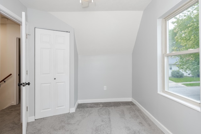 bonus room featuring light carpet, lofted ceiling, and a healthy amount of sunlight