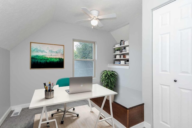 carpeted office featuring lofted ceiling, ceiling fan, and a textured ceiling