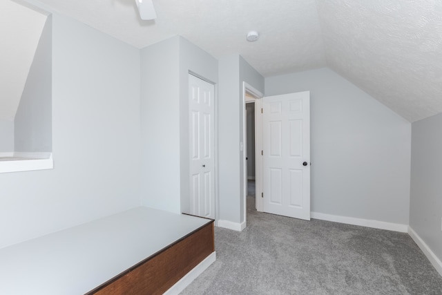 bonus room with a textured ceiling, lofted ceiling, and light colored carpet