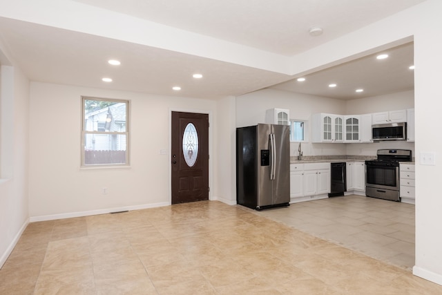 interior space with sink, light tile patterned floors, stainless steel appliances, and white cabinets