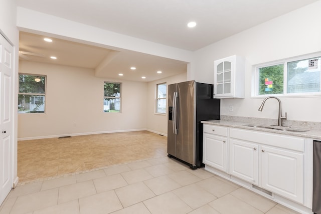 kitchen with light stone countertops, stainless steel appliances, white cabinets, and sink