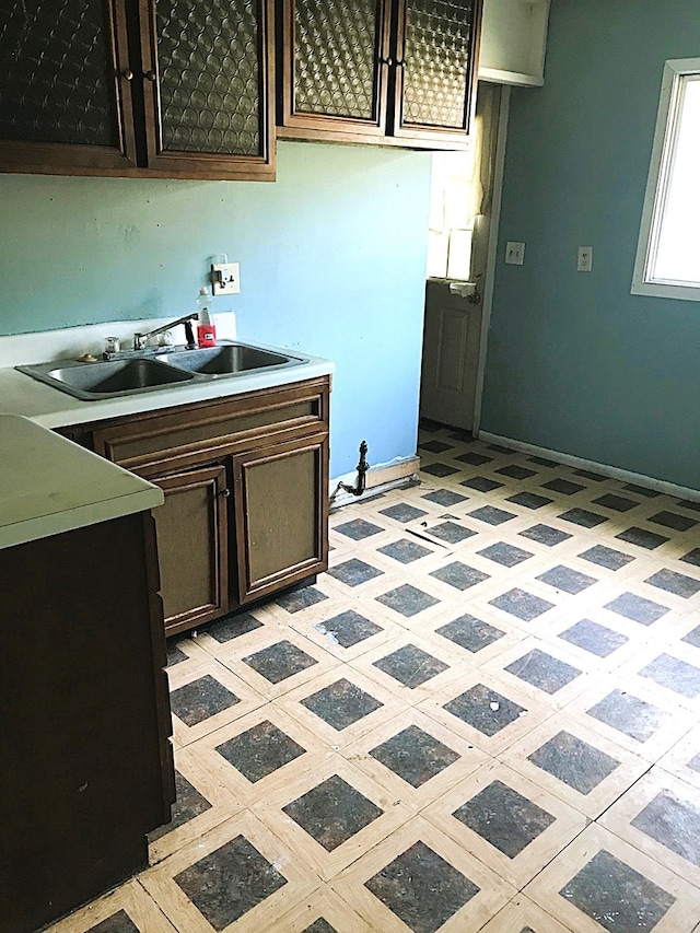 kitchen with sink, dark brown cabinetry, and light tile patterned flooring