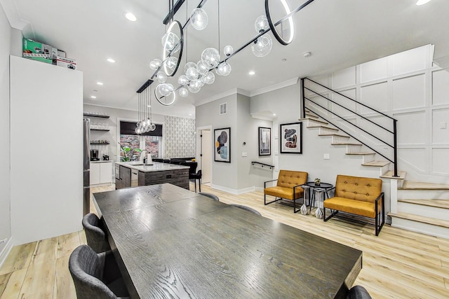 dining area featuring an inviting chandelier, light hardwood / wood-style floors, and crown molding