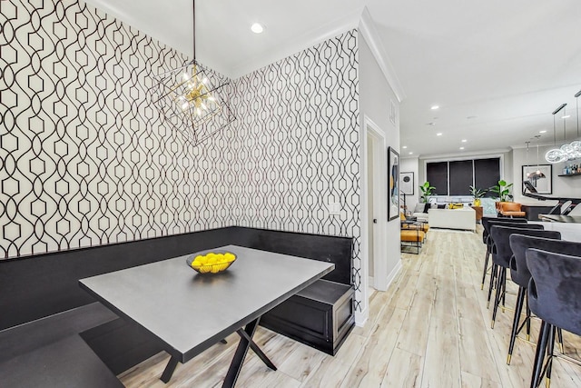 dining area with an inviting chandelier, light hardwood / wood-style floors, and ornamental molding