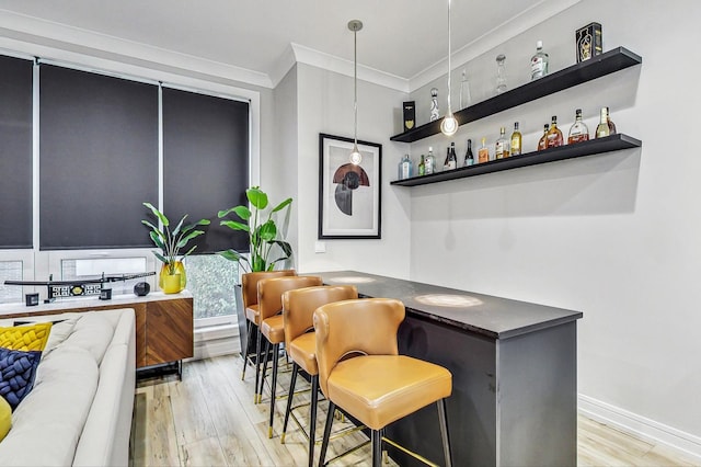 bar with light hardwood / wood-style floors, hanging light fixtures, and crown molding