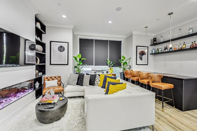 living room featuring bar area, light wood-type flooring, and crown molding