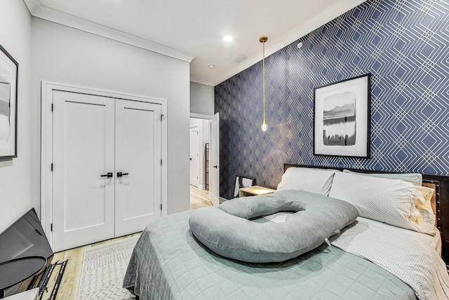 bedroom featuring crown molding, light hardwood / wood-style floors, and a closet