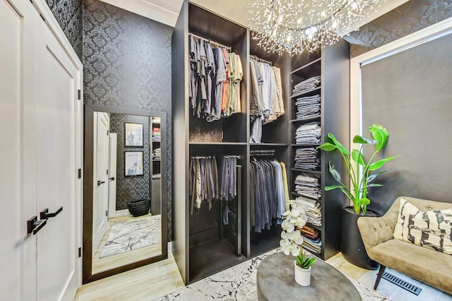 walk in closet featuring a notable chandelier and light hardwood / wood-style flooring