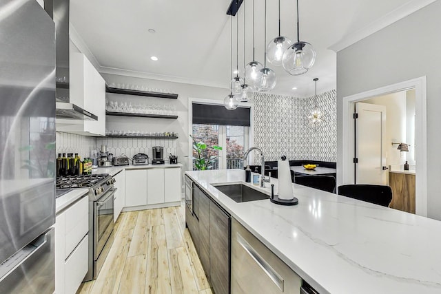 kitchen featuring white cabinets, pendant lighting, stainless steel appliances, light hardwood / wood-style flooring, and sink